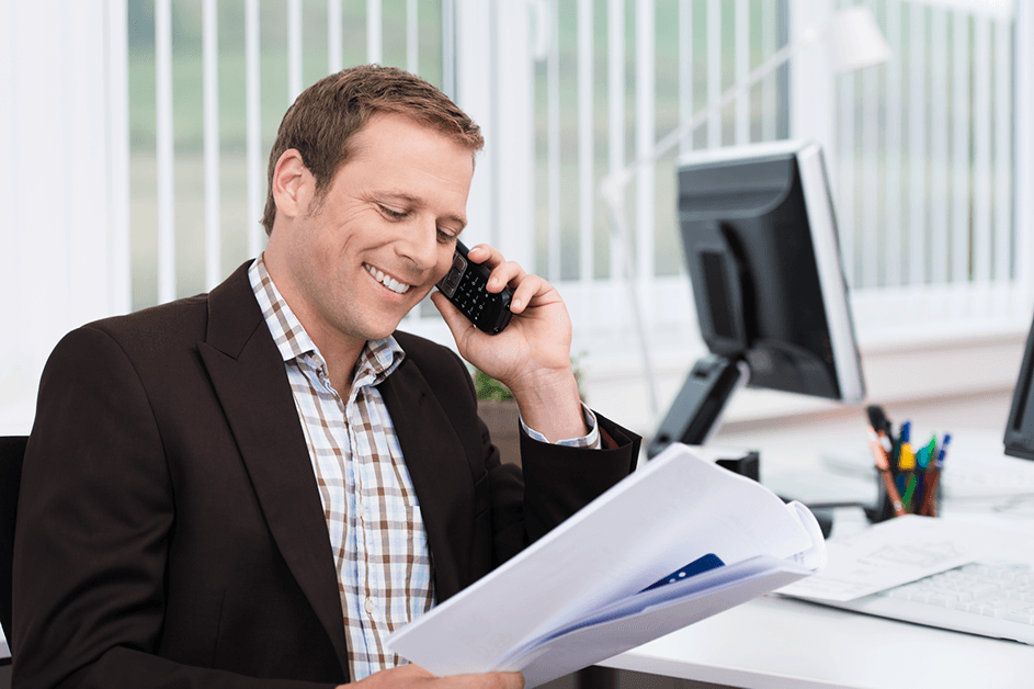 Zakenman aan de telefoon kijkt met tevreden glimlach naar een document in zijn hand